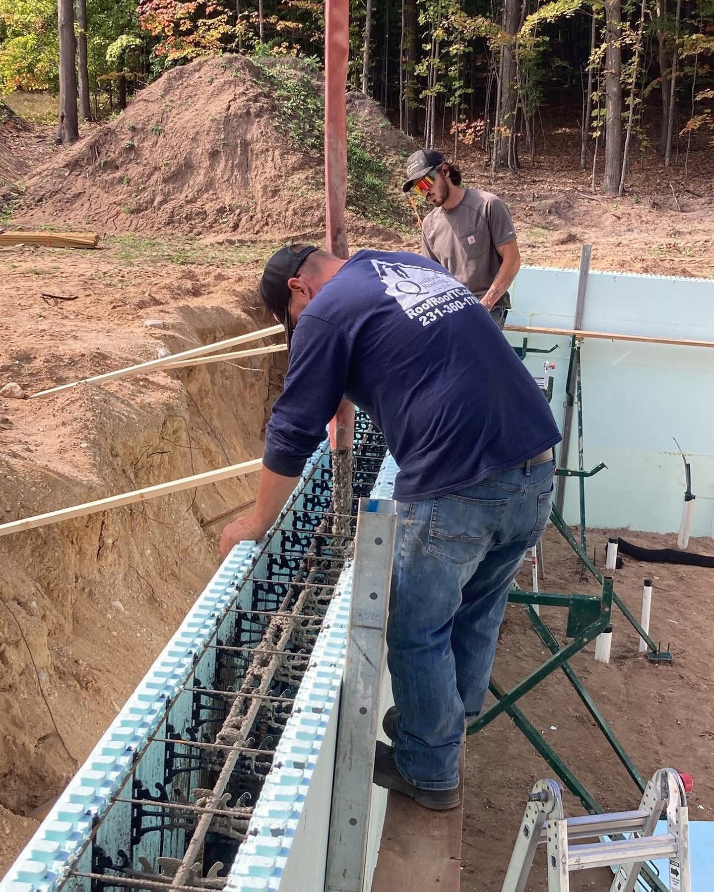 Worker setting rebar in an insulated concrete foundation wall